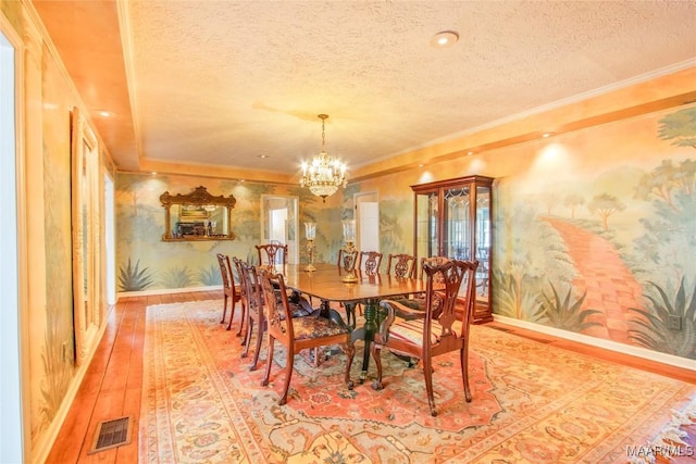 601 N Pickett St, Autaugaville, AL 36003 - dining room with visible vents, a chandelier, crown molding, hardwood / wood-style flooring, and wallpapered walls