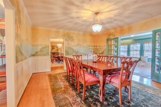 dining room with ornamental molding, an inviting chandelier, and light hardwood / wood-style floors