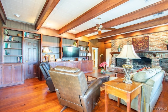 living room with beam ceiling, ceiling fan, hardwood / wood-style floors, and a fireplace