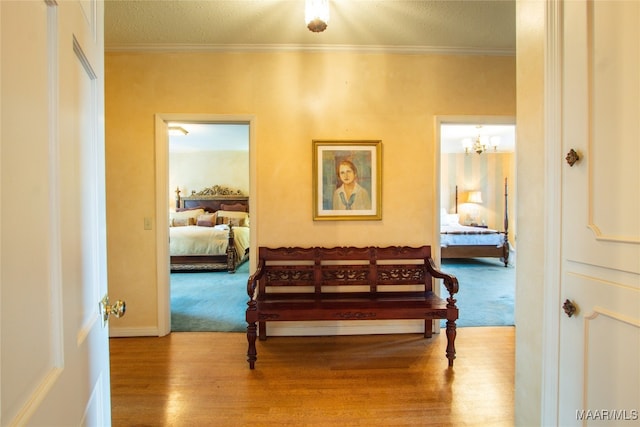 hall featuring a textured ceiling, crown molding, hardwood / wood-style floors, and a chandelier