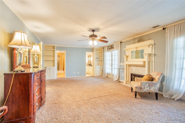 living area with ornamental molding, ceiling fan, carpet floors, and a fireplace