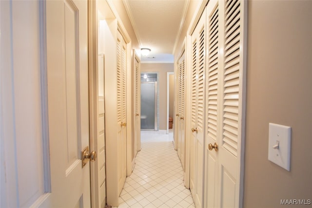 hallway featuring ornamental molding, a textured ceiling, and light tile patterned flooring