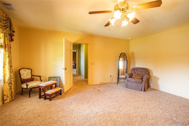 living area with ceiling fan, light colored carpet, and ornamental molding