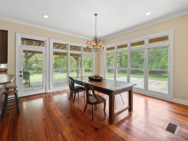 dining space featuring crown molding, hardwood / wood-style floors, and a notable chandelier