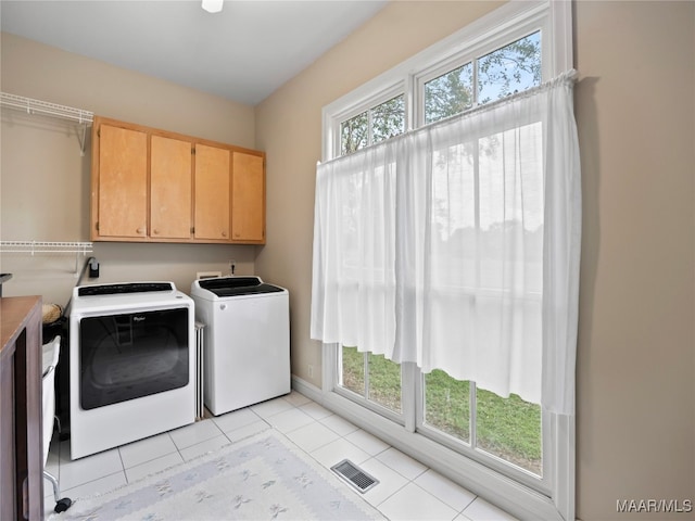 laundry area featuring light tile patterned floors, cabinets, plenty of natural light, and washer and dryer