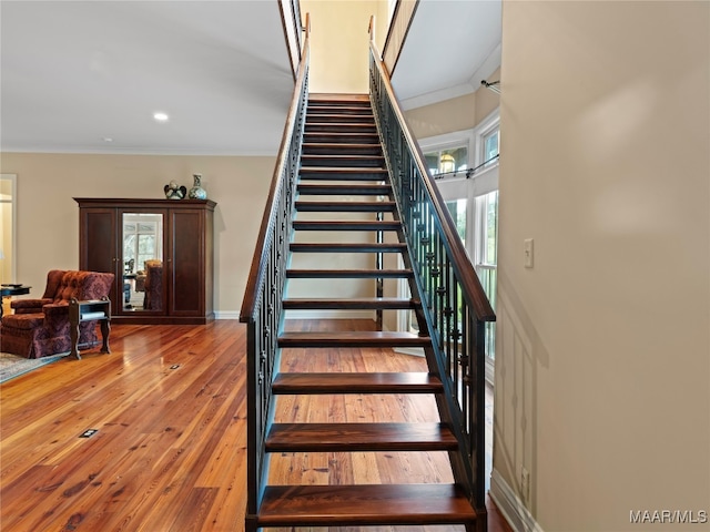 stairs featuring hardwood / wood-style flooring, plenty of natural light, and ornamental molding