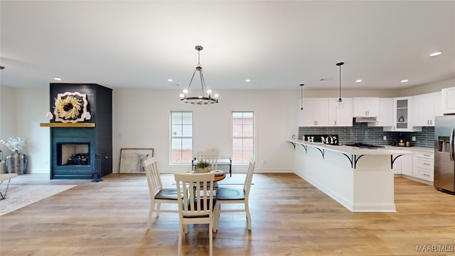 kitchen featuring a chandelier, light hardwood / wood-style floors, white cabinetry, and a breakfast bar