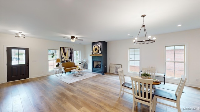 dining room featuring ceiling fan with notable chandelier, a fireplace, and plenty of natural light