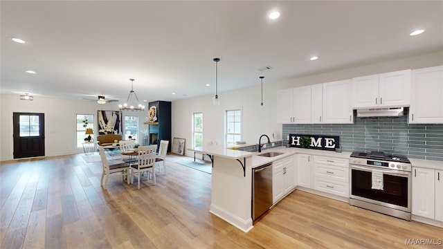 kitchen featuring white cabinets, kitchen peninsula, stainless steel appliances, light hardwood / wood-style flooring, and decorative light fixtures