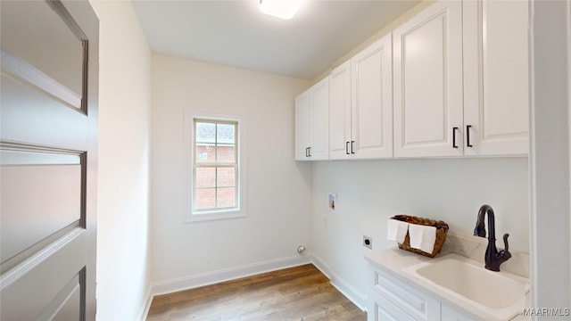 washroom featuring washer hookup, hookup for an electric dryer, cabinets, sink, and light hardwood / wood-style flooring