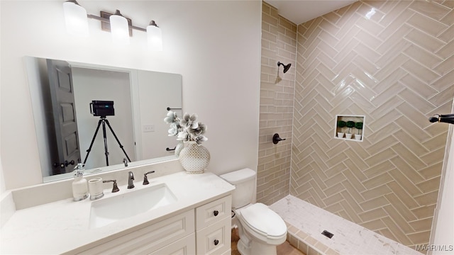 bathroom featuring vanity, toilet, and tiled shower