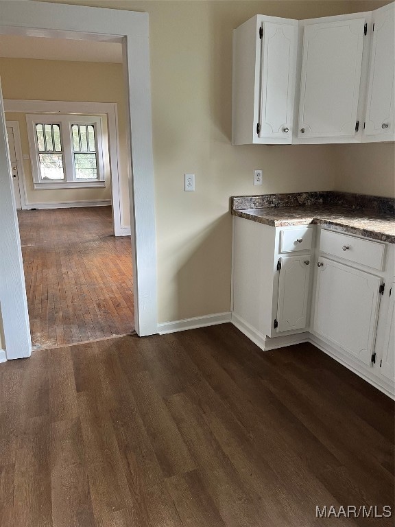 kitchen with dark hardwood / wood-style flooring and white cabinetry