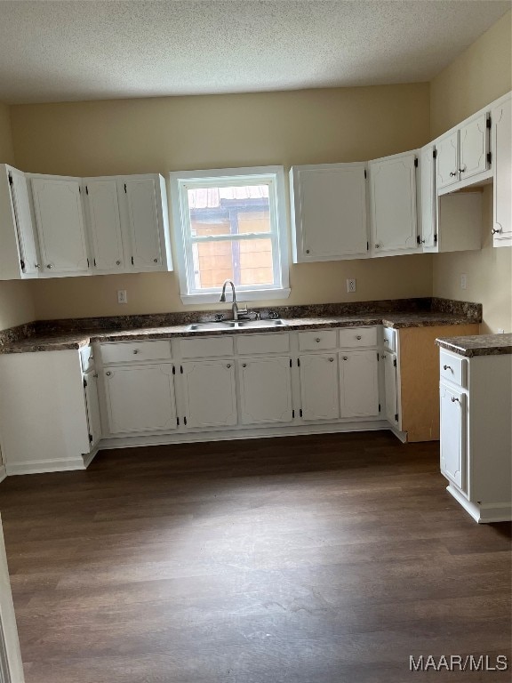 kitchen featuring dark hardwood / wood-style floors, a textured ceiling, sink, and white cabinets