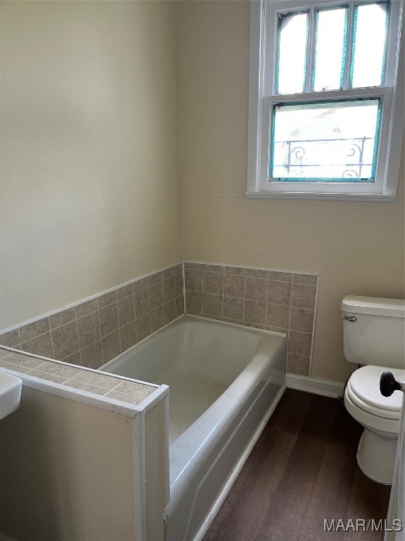 bathroom featuring a bathtub, toilet, and hardwood / wood-style flooring