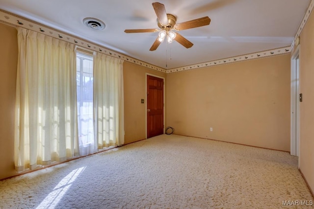 carpeted spare room featuring a wealth of natural light and ceiling fan