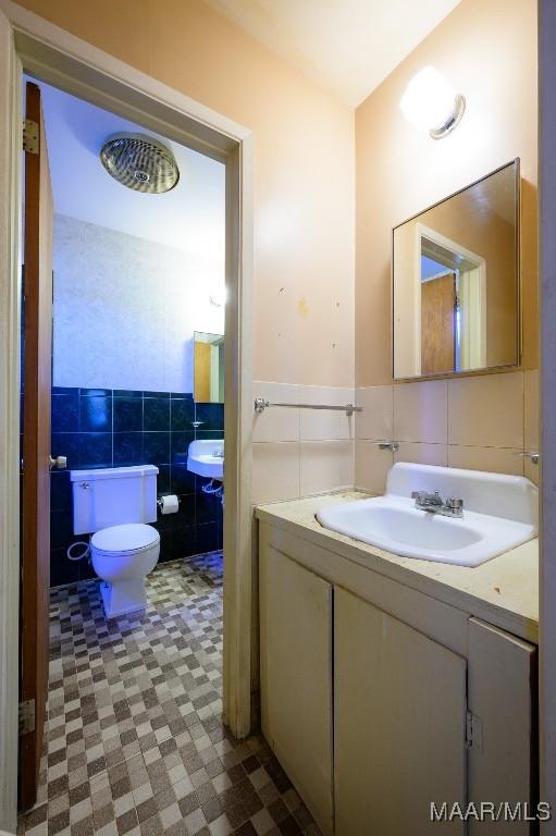 bathroom with toilet, tile walls, and sink