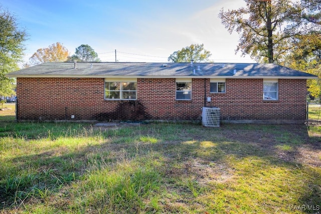 rear view of property featuring a yard and central air condition unit