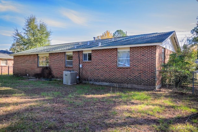 rear view of house with a yard and central AC