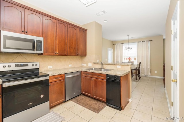 kitchen featuring decorative light fixtures, sink, kitchen peninsula, stainless steel appliances, and light stone countertops