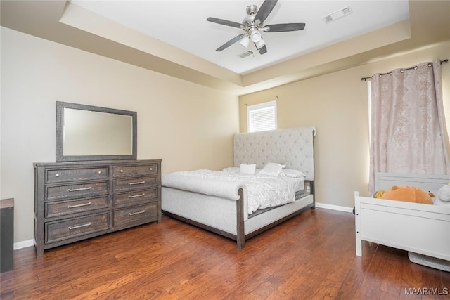 bedroom featuring dark wood-type flooring, ceiling fan, and a raised ceiling