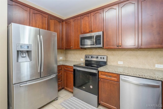 kitchen with tasteful backsplash, light stone countertops, appliances with stainless steel finishes, and light tile patterned floors