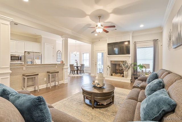 living room featuring ornamental molding, decorative columns, light hardwood / wood-style floors, and ceiling fan