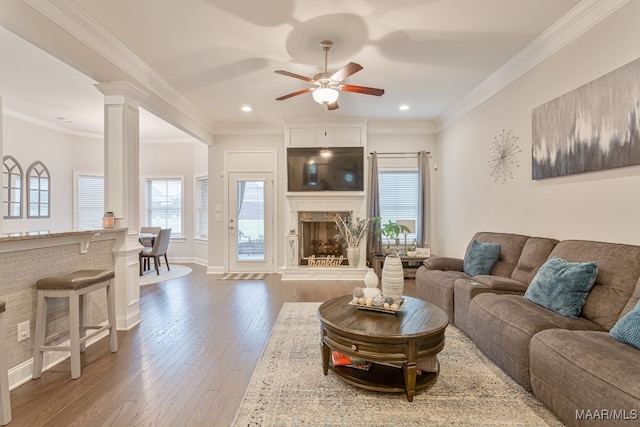 living room with dark hardwood / wood-style flooring, a high end fireplace, decorative columns, crown molding, and ceiling fan