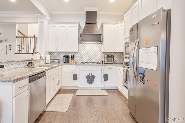 kitchen with white cabinetry, light stone counters, stainless steel appliances, light wood-type flooring, and premium range hood