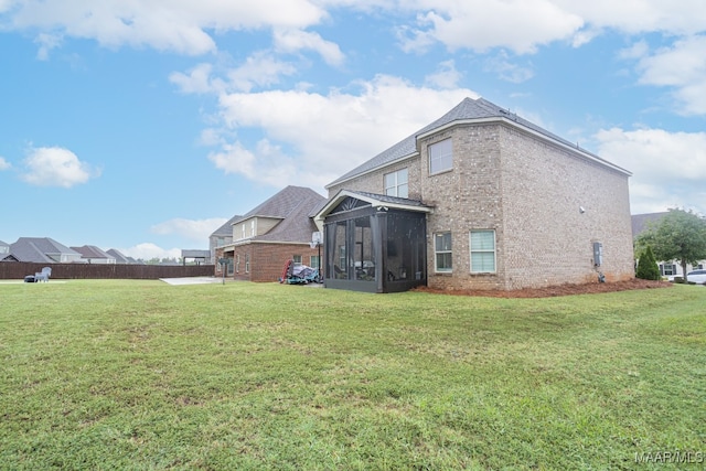 rear view of house with a sunroom and a lawn