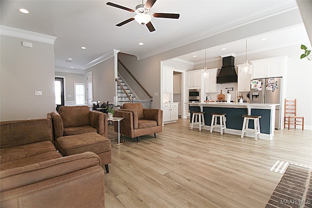 living room featuring light wood-type flooring, ceiling fan, and crown molding