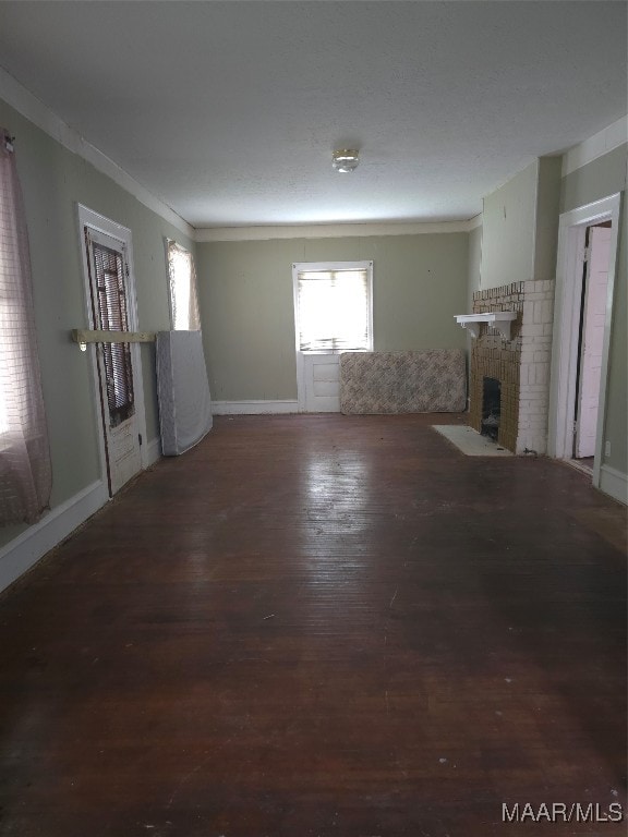 unfurnished living room with ornamental molding, a brick fireplace, and hardwood / wood-style floors