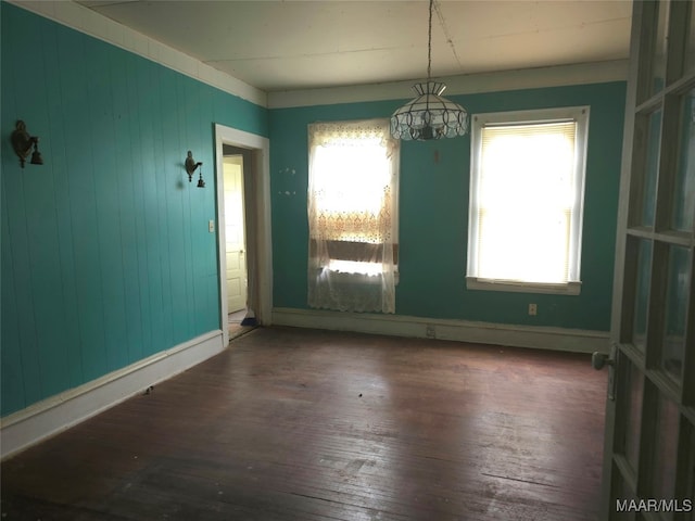 spare room with an inviting chandelier, dark hardwood / wood-style floors, and wood walls