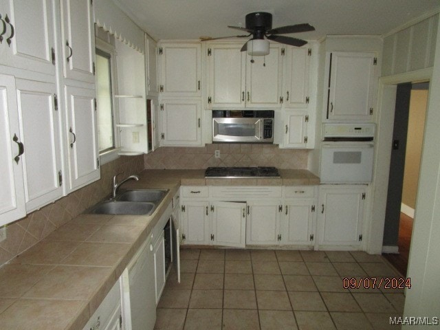 kitchen with ceiling fan, sink, stainless steel appliances, tile counters, and decorative backsplash