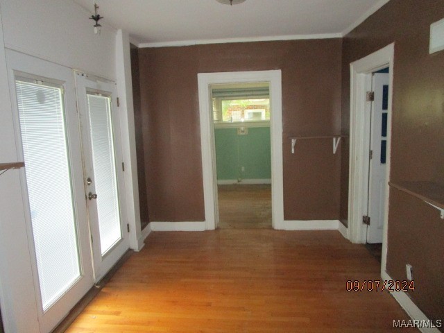 hall featuring a healthy amount of sunlight, ornamental molding, and light hardwood / wood-style flooring