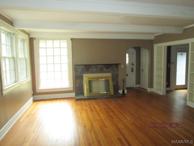 unfurnished living room with beamed ceiling, hardwood / wood-style floors, and a healthy amount of sunlight