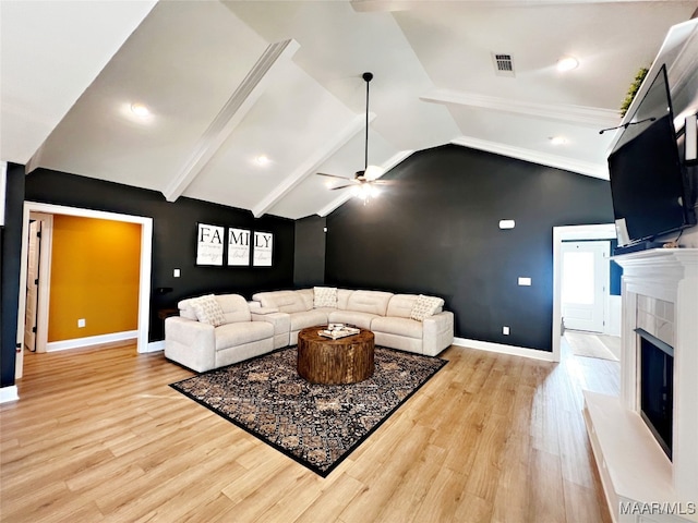 living room featuring vaulted ceiling with beams, a premium fireplace, light hardwood / wood-style floors, and ceiling fan