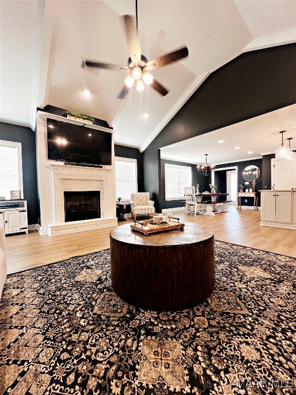 living room with light hardwood / wood-style flooring, vaulted ceiling, ceiling fan, and a fireplace