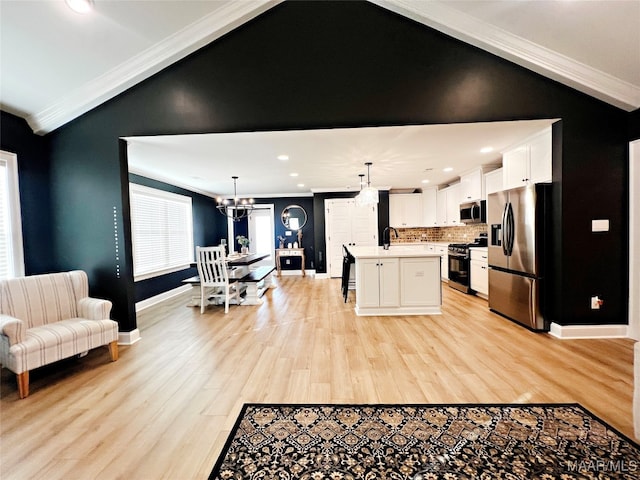 kitchen featuring appliances with stainless steel finishes, crown molding, a kitchen island with sink, and hanging light fixtures