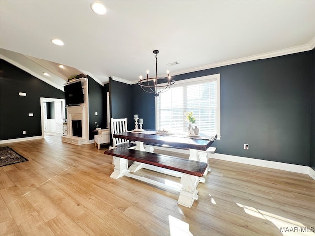 dining room featuring light wood-type flooring, lofted ceiling, ornamental molding, and a chandelier