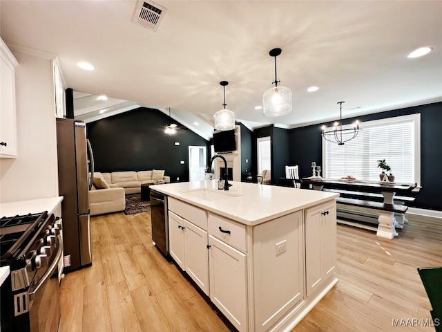 kitchen with white cabinets, an island with sink, pendant lighting, light hardwood / wood-style flooring, and stainless steel appliances