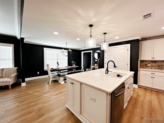 kitchen featuring stainless steel dishwasher, a kitchen island with sink, sink, and decorative light fixtures