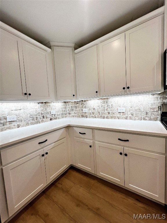 kitchen featuring white cabinets, dark wood-type flooring, and tasteful backsplash