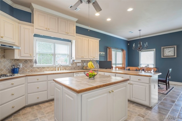 kitchen with kitchen peninsula, tile countertops, decorative light fixtures, a kitchen island, and plenty of natural light