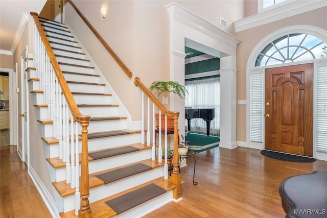 foyer with a high ceiling, crown molding, and wood-type flooring