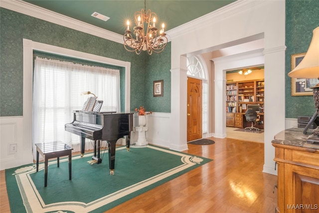 misc room featuring hardwood / wood-style floors, built in shelves, ornamental molding, and a chandelier