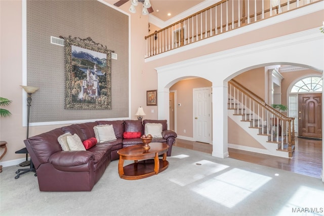 living room featuring ornate columns, ceiling fan, a towering ceiling, and wood-type flooring