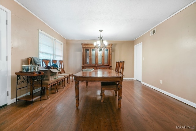 dining space with crown molding, an inviting chandelier, and dark wood-type flooring