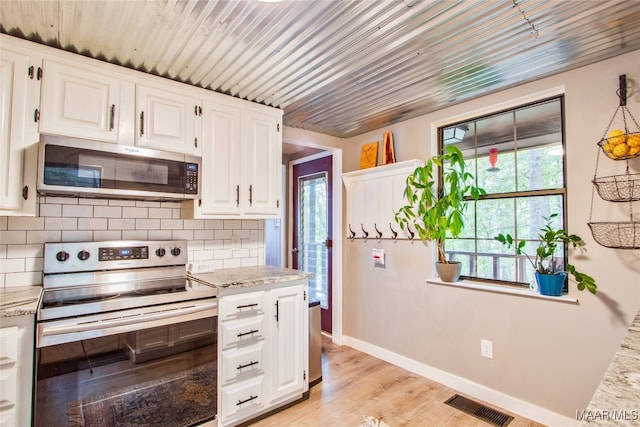 kitchen featuring white cabinets, light wood-type flooring, stainless steel appliances, and backsplash