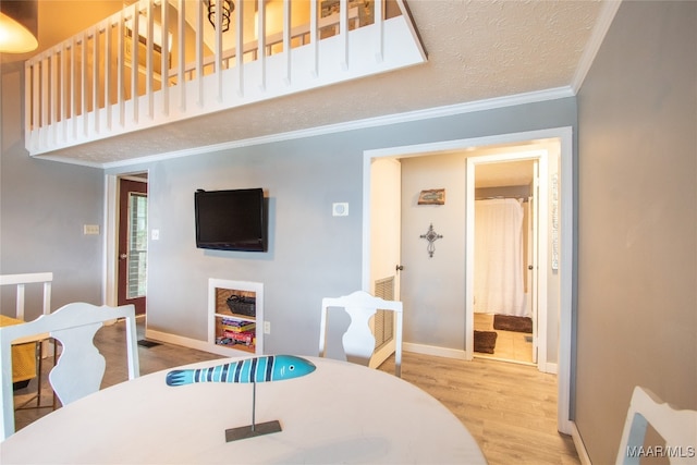 dining space featuring light hardwood / wood-style flooring, a textured ceiling, and ornamental molding