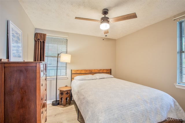 bedroom featuring ceiling fan, a textured ceiling, and light wood-type flooring